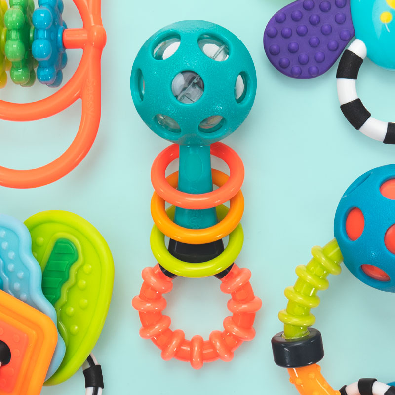 a collection of rattles and teethers shown overhead on a light blue background.