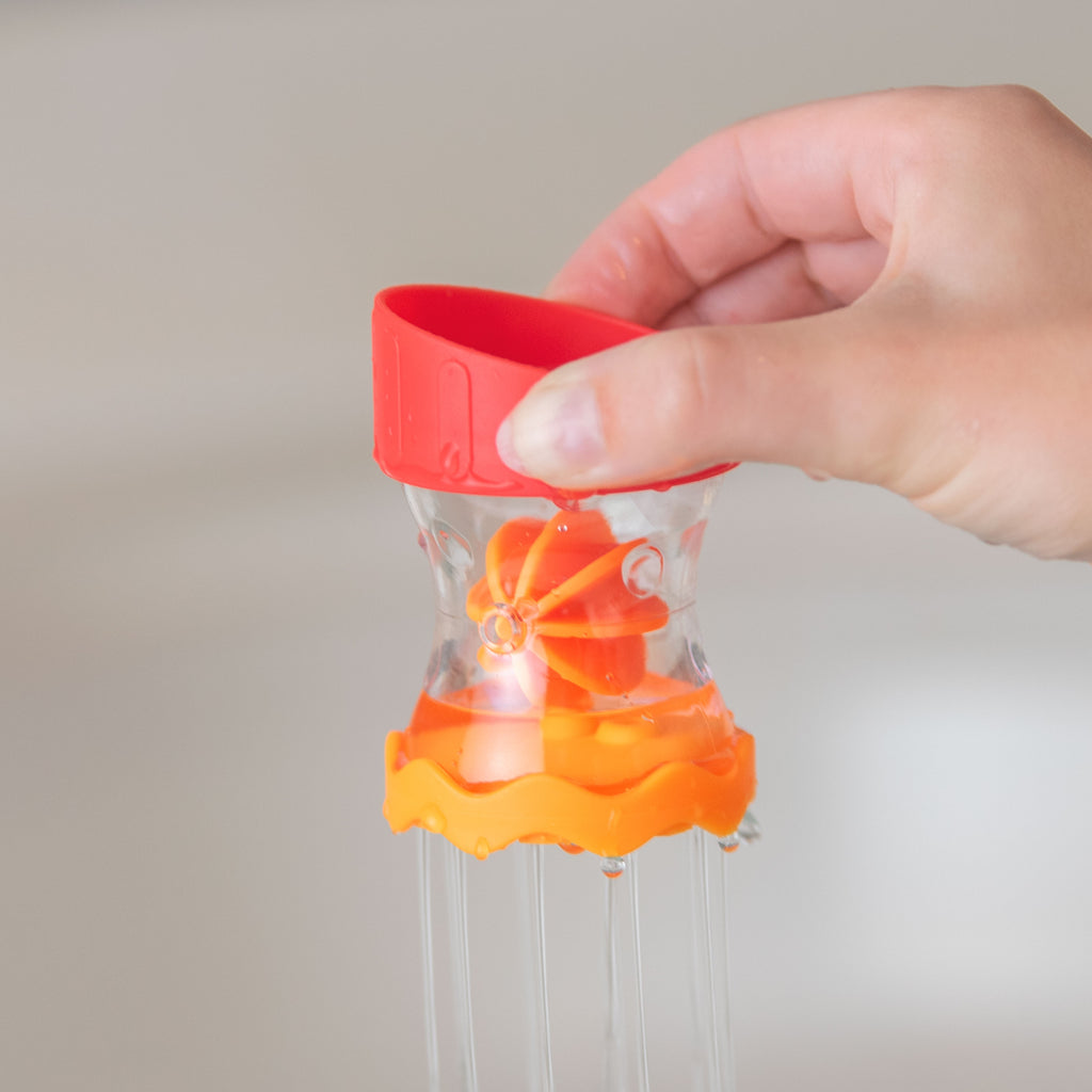 hand holding bath toy with water coming out of the bottom of the toy