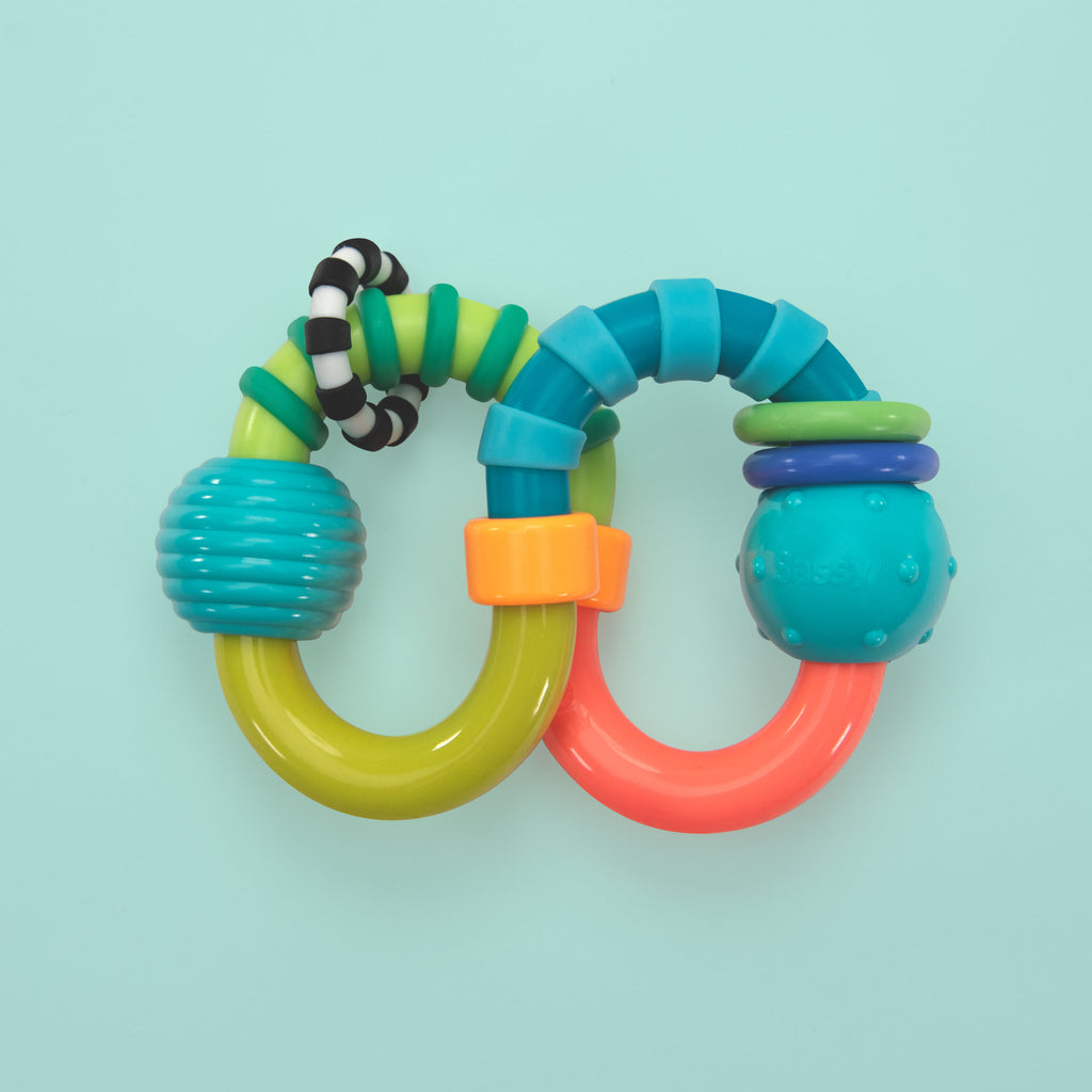 a figured eight shaped teether with multiple textures and colored. there are two balls on the ends of the teether and a black and white striped ring attached to the teether.