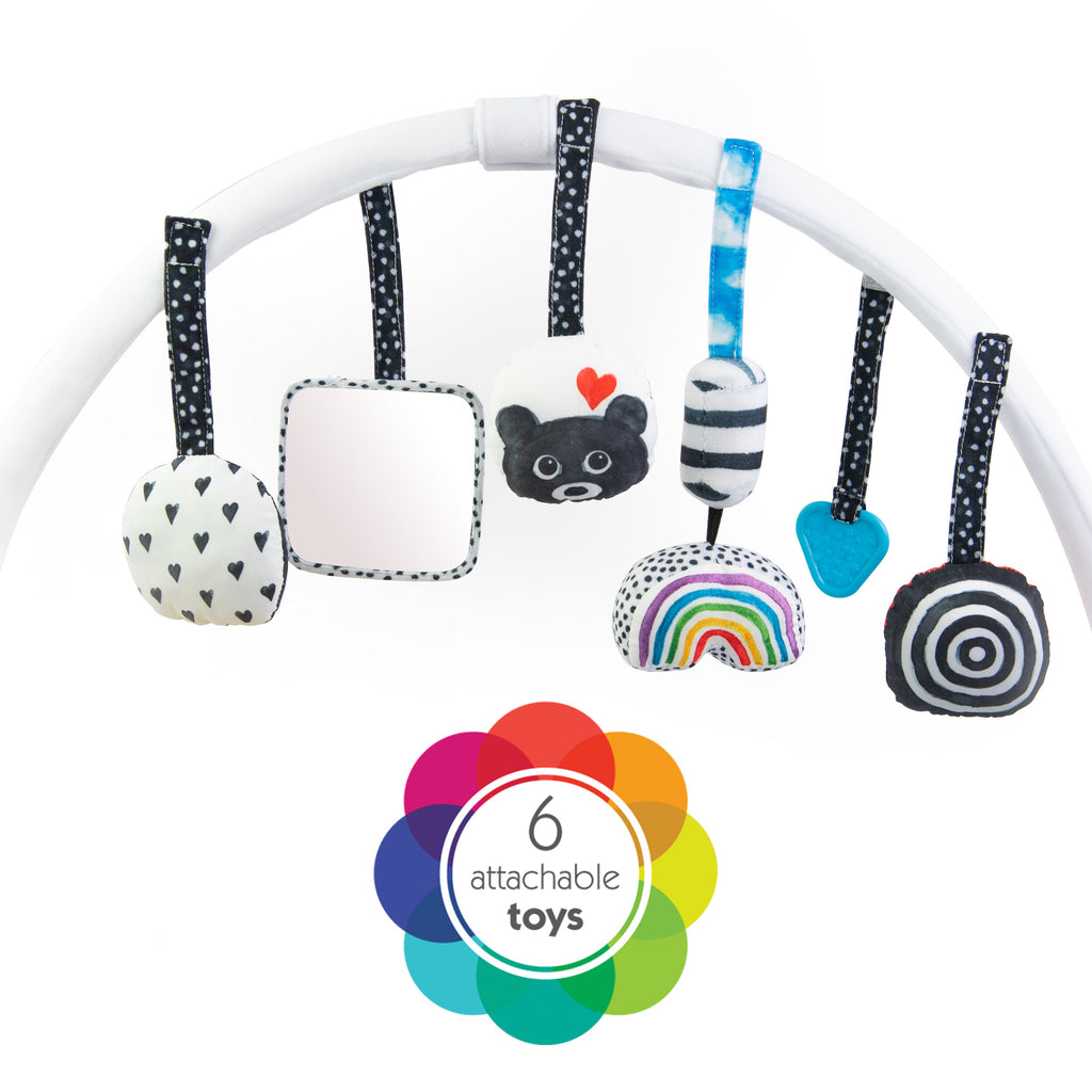 6 attachable hanging toys hanging from the archway of the playmat.
black and white circle with hearts, mirror, round toy with a bear, rainbow toy, blue teether, and black and white bullseye.