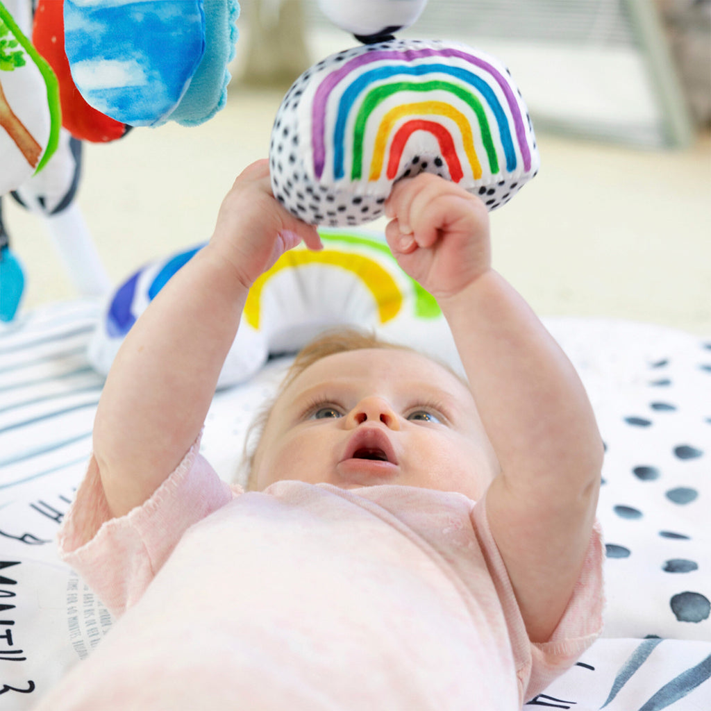 baby playing with rainbow hanging toy