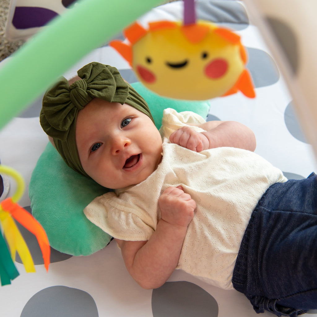 baby smiling at camera laying on playmat