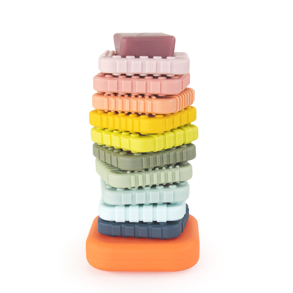 a ring stacker with an dusty orange base and a dusty purple post that is twisted. there are 10 different dusty colored and textured rings in rainbow order. 