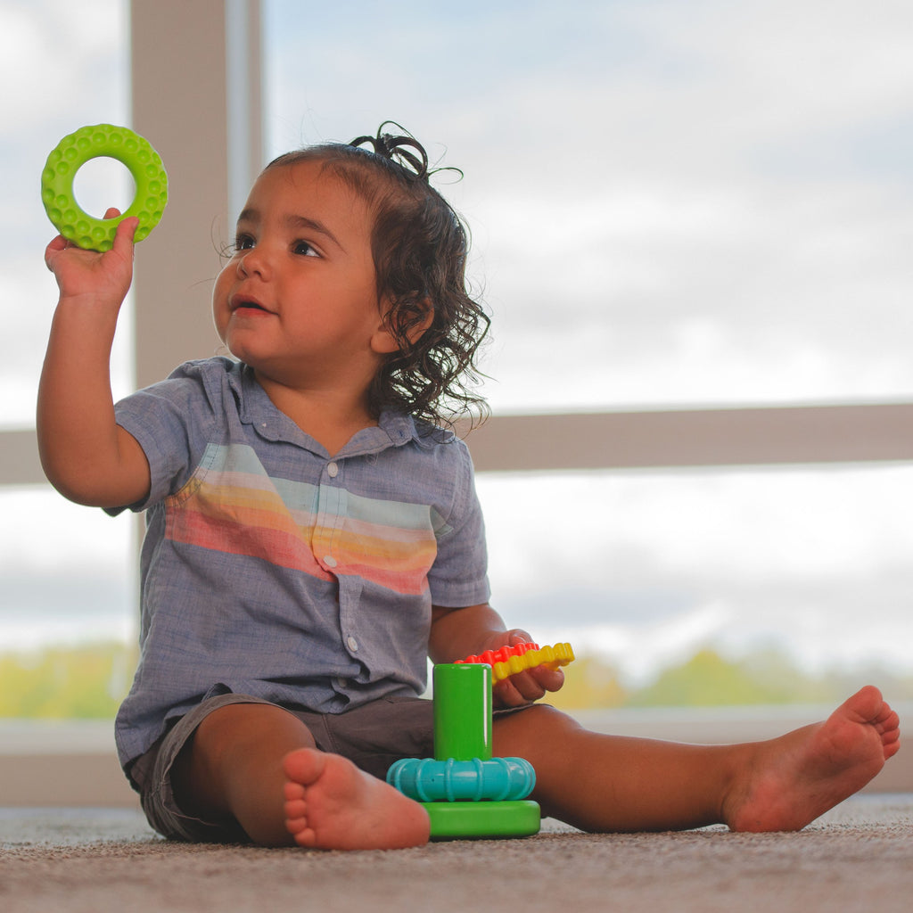 kid playing with multicolored stacker