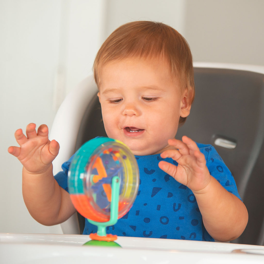 baby at highchair playing with a spinning wheel