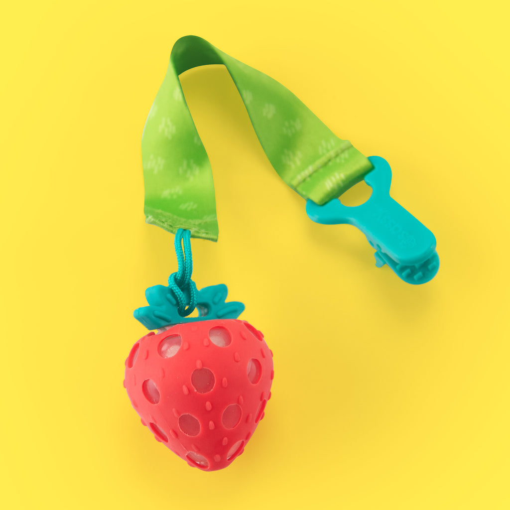 a strawberry silicone teether that has a clear water filled inside. there isa green patterned fabric strap with a blue clip to attach on the go. 