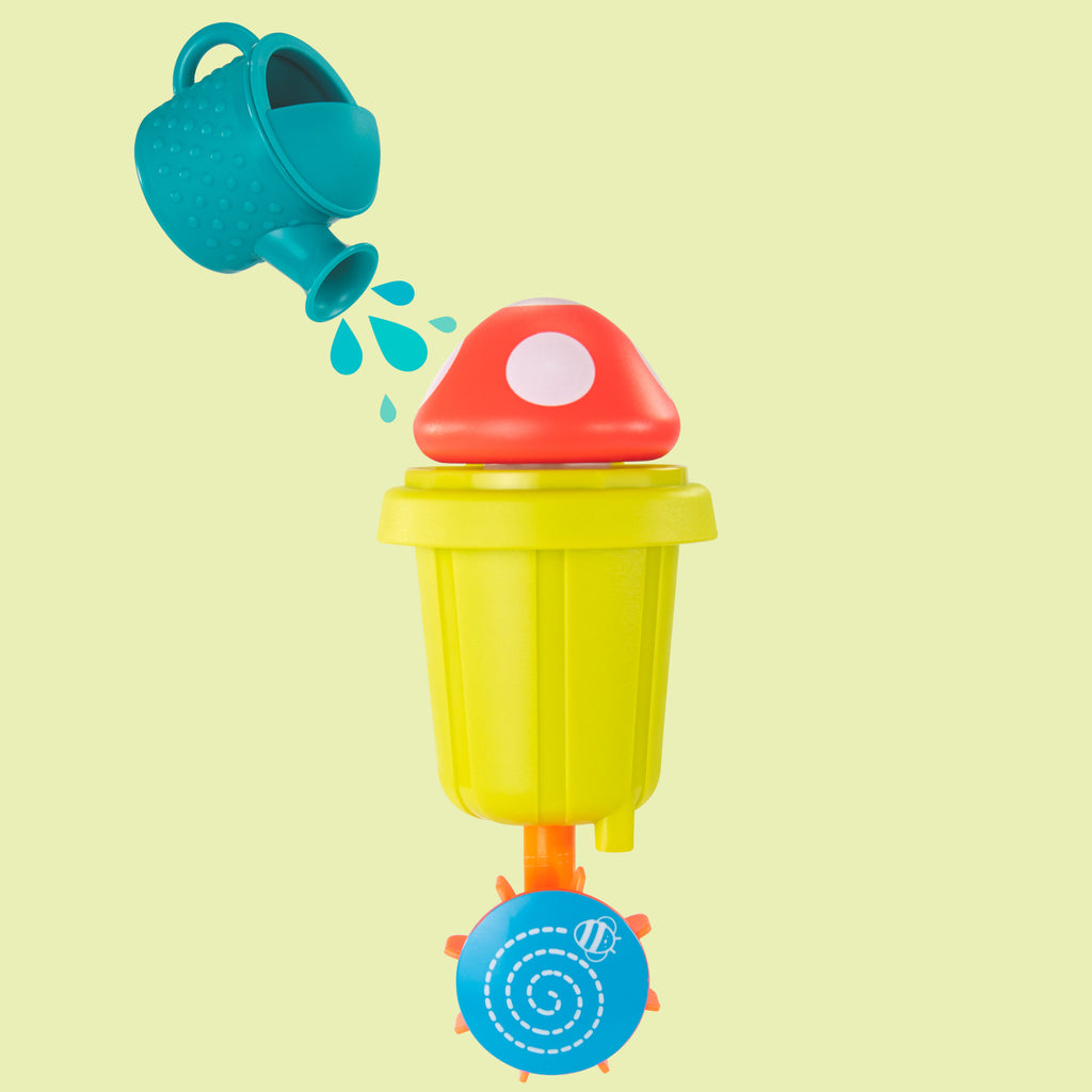 a mushroom water toy featuring a blue watering can designed to pour water over a red and white mushroom, causing it to pop up. water flows through the bright green cylinder of the toy and falls onto an orange and blue spinner at the bottom, which is illustrated with a bee and bee line.