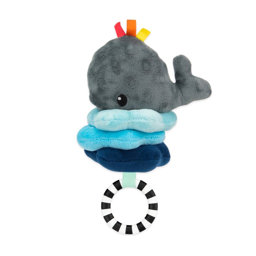 a soft four-piece jitter toy featuring a small whale atop three colorful ribbons, with three stacked ombre waves beneath it. a black-and-white ring can be pulled down to make the whale jitter.